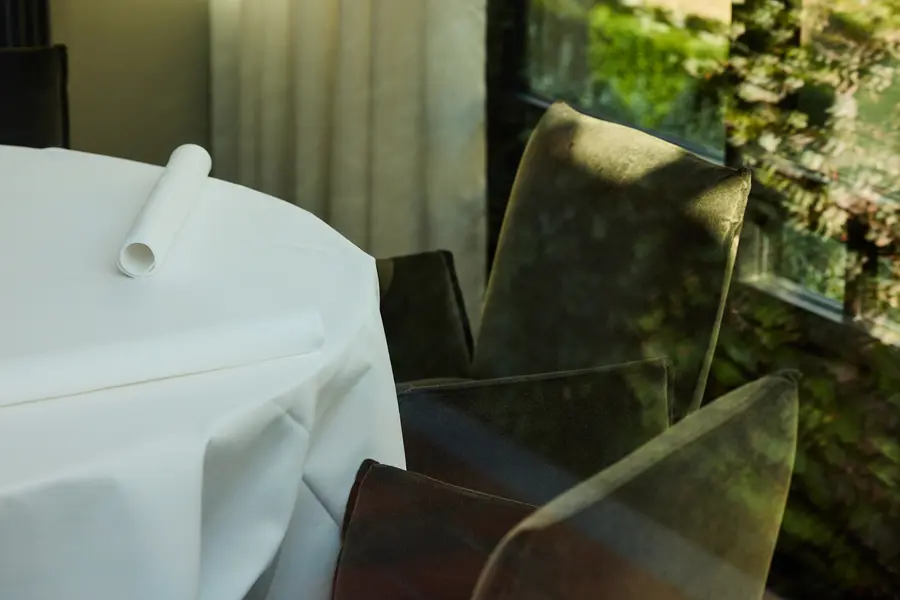 Gedekte tafel met wit linnen bij het raam, met zicht op het groen