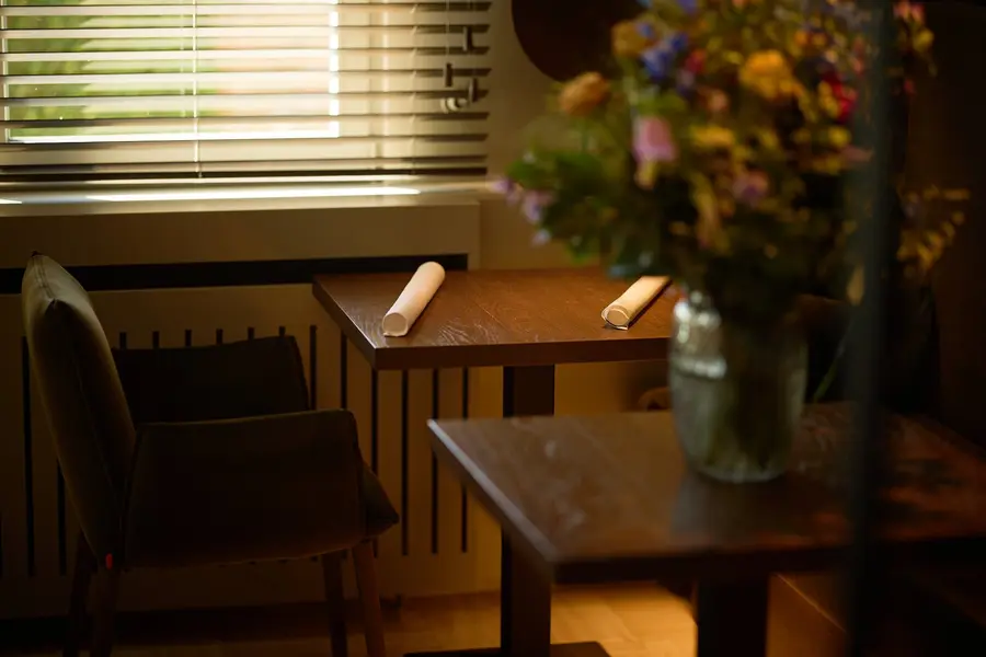 Een tafel met een boeket veldbloemen bij het raam
