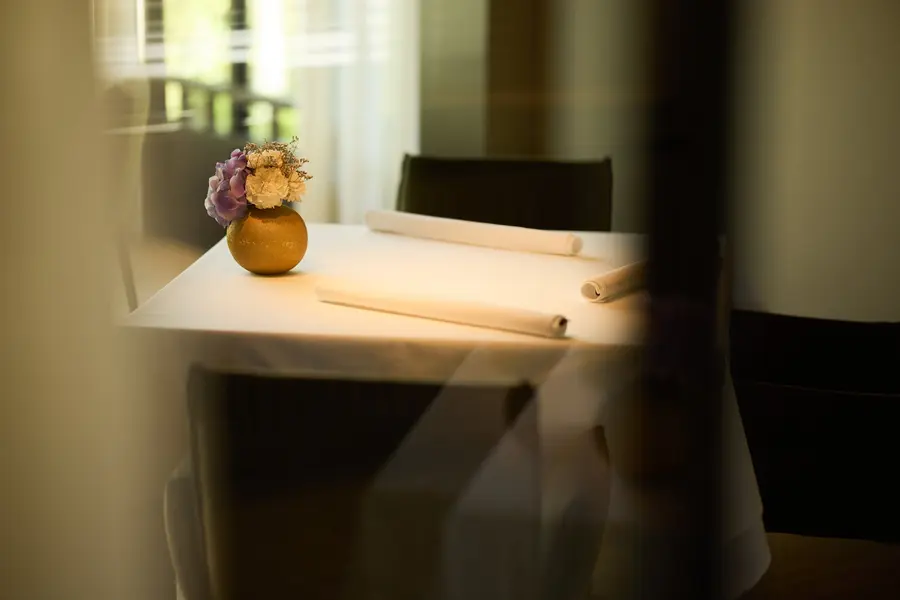 Een tafel met een vaasje bloemen in het warme licht