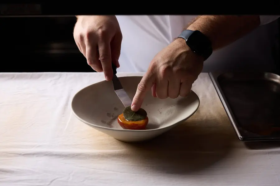 De chef dresseert een gerecht aan tafel