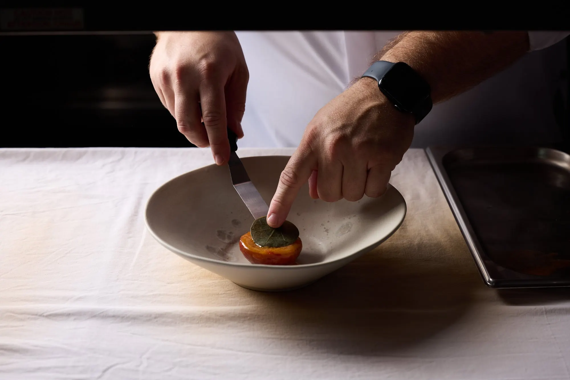 De chef dresseert een gerecht aan tafel