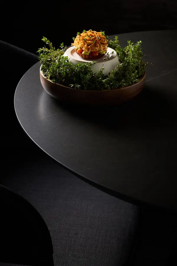Een gerecht met een krokante garnituur op een donkere tafel